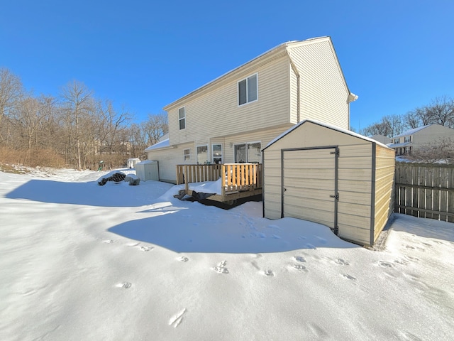 snow covered house featuring a wooden deck and a shed