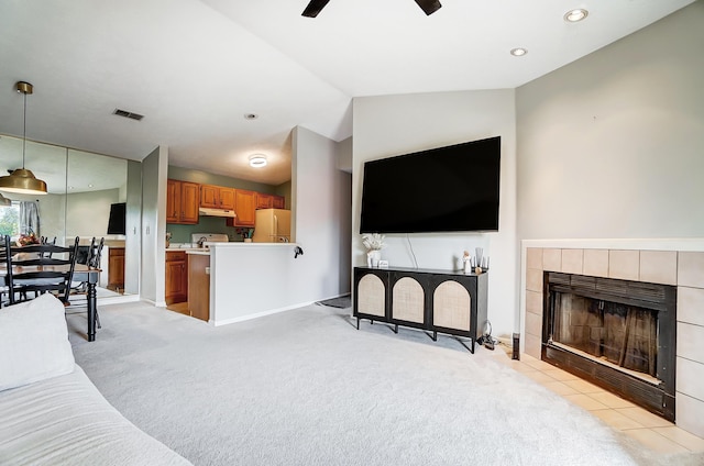 carpeted living room with ceiling fan, a fireplace, and vaulted ceiling