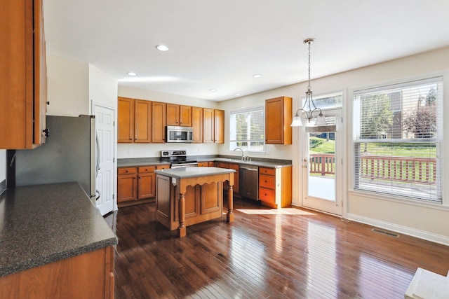 kitchen featuring sink, a kitchen island, dark hardwood / wood-style flooring, pendant lighting, and appliances with stainless steel finishes