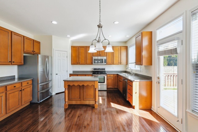 kitchen with sink, decorative light fixtures, a center island, dark hardwood / wood-style flooring, and appliances with stainless steel finishes