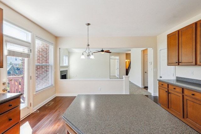 kitchen with ceiling fan with notable chandelier, dark hardwood / wood-style flooring, and decorative light fixtures