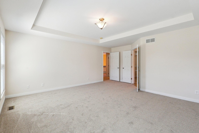 carpeted empty room with a tray ceiling