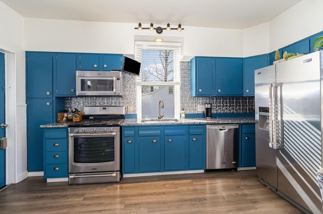 kitchen featuring appliances with stainless steel finishes, blue cabinets, backsplash, and sink