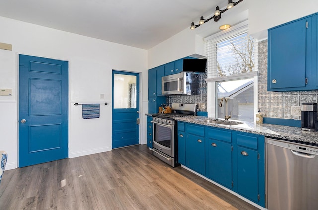 kitchen featuring stainless steel appliances, blue cabinets, sink, tasteful backsplash, and wood-type flooring