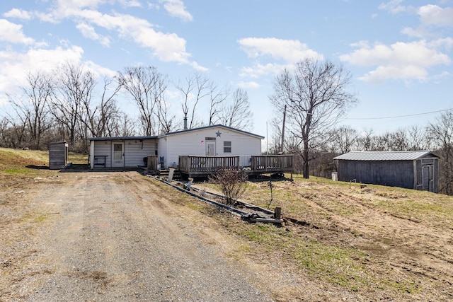 manufactured / mobile home with an outbuilding, dirt driveway, and a wooden deck