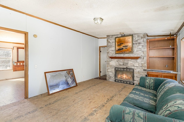 living area featuring a textured ceiling, a stone fireplace, and crown molding