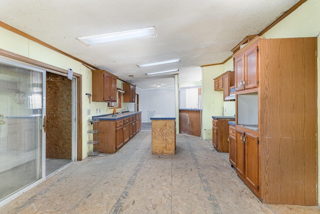 kitchen with a center island, ornamental molding, brown cabinets, a textured ceiling, and a sink