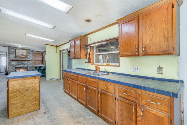 kitchen featuring brown cabinets, a fireplace, and a sink