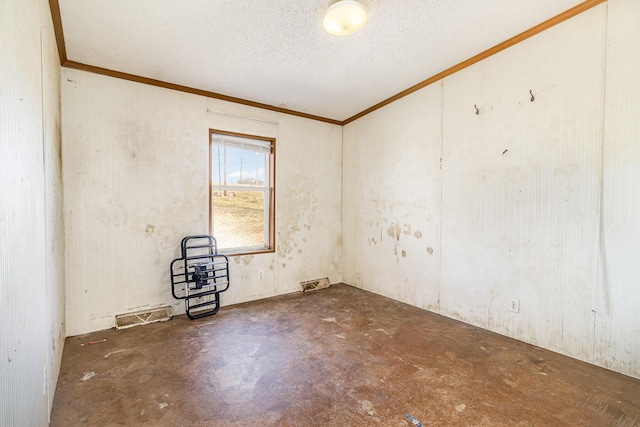 empty room featuring visible vents, a textured ceiling, ornamental molding, and unfinished concrete floors