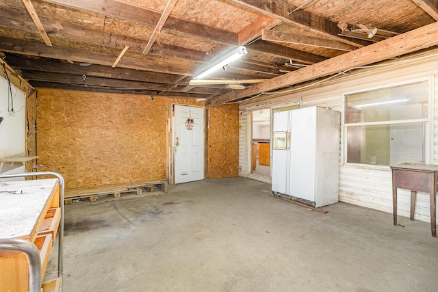 basement featuring white fridge with ice dispenser