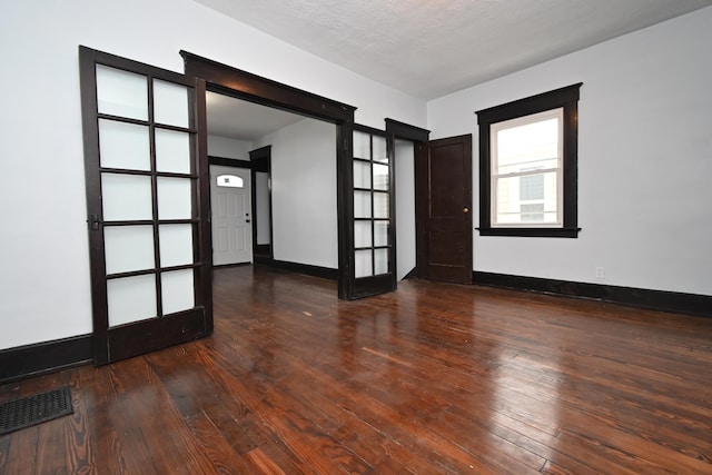 unfurnished room with dark wood-type flooring, a textured ceiling, and french doors