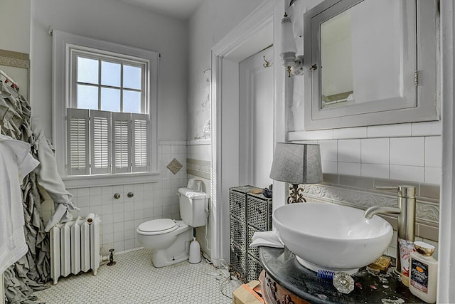 bathroom with toilet, vanity, tile patterned flooring, tile walls, and radiator