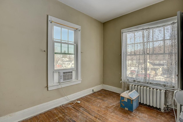 empty room with radiator, cooling unit, and wood-type flooring