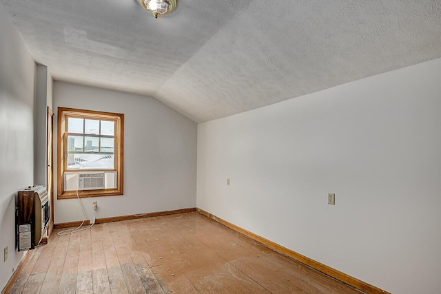 additional living space featuring a textured ceiling, light hardwood / wood-style flooring, lofted ceiling, and cooling unit