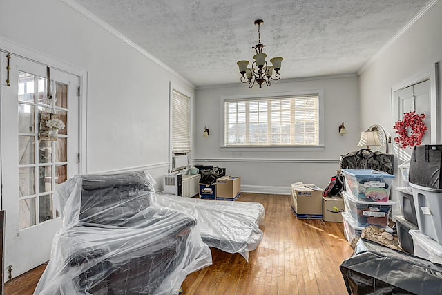 bedroom featuring hardwood / wood-style floors, ornamental molding, a chandelier, and a textured ceiling