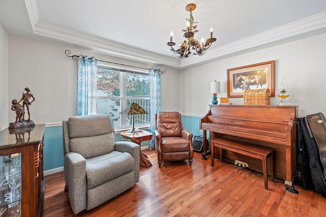 living area featuring hardwood / wood-style flooring, crown molding, a raised ceiling, and a notable chandelier