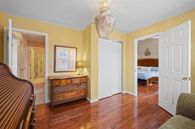 bedroom with a notable chandelier, dark hardwood / wood-style flooring, and a closet