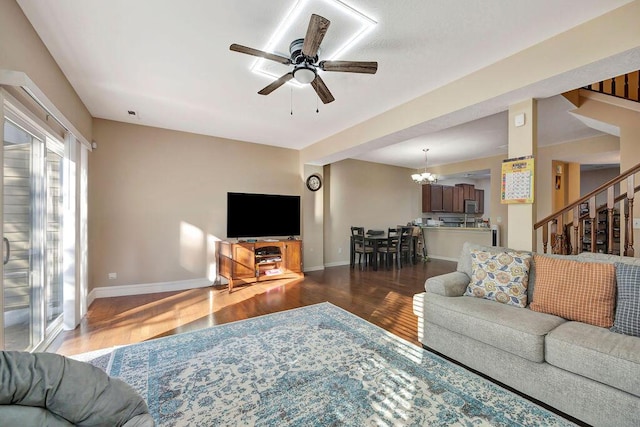 living room with dark wood-type flooring and ceiling fan with notable chandelier