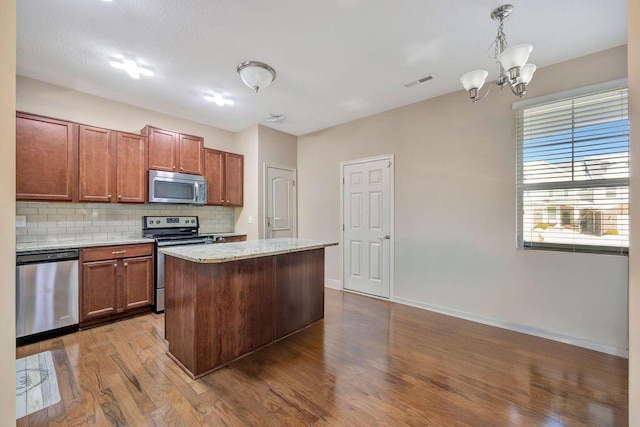 kitchen with tasteful backsplash, a notable chandelier, pendant lighting, a center island, and appliances with stainless steel finishes