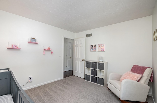 carpeted bedroom featuring a textured ceiling and a crib