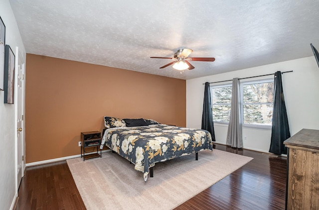 bedroom with a textured ceiling, ceiling fan, and dark hardwood / wood-style floors