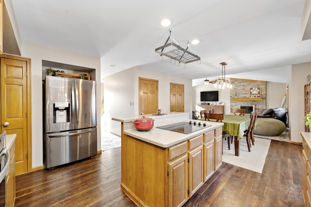 kitchen featuring dark hardwood / wood-style floors, a brick fireplace, black electric stovetop, a kitchen island, and stainless steel refrigerator with ice dispenser