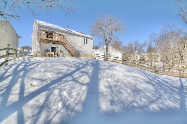 snow covered rear of property with a wooden deck