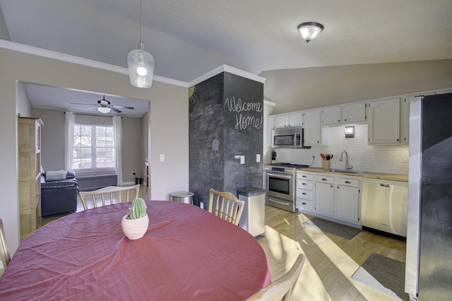 dining space with light wood-type flooring, vaulted ceiling, sink, and ceiling fan