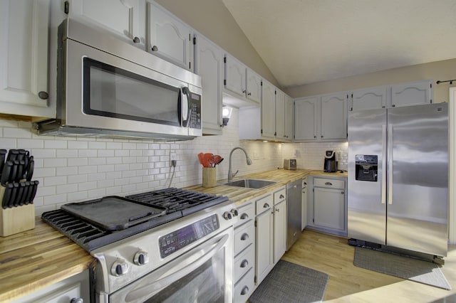 kitchen featuring appliances with stainless steel finishes, lofted ceiling, decorative backsplash, and sink