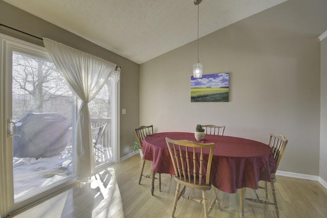 dining area with vaulted ceiling, a textured ceiling, a healthy amount of sunlight, and light wood-type flooring