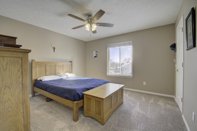 bedroom featuring a textured ceiling, ceiling fan, and light colored carpet