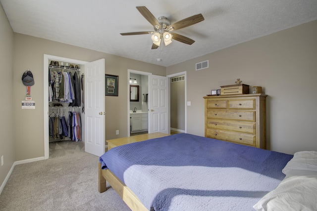 carpeted bedroom with ceiling fan, sink, connected bathroom, a textured ceiling, and a closet