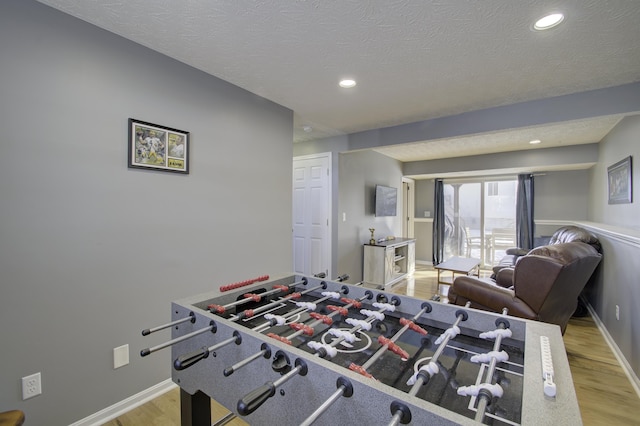 playroom with a textured ceiling and light hardwood / wood-style flooring