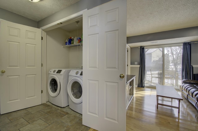 laundry area with washing machine and dryer and a textured ceiling