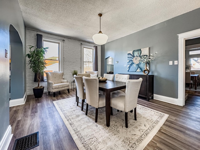 dining room featuring a textured ceiling and dark hardwood / wood-style floors