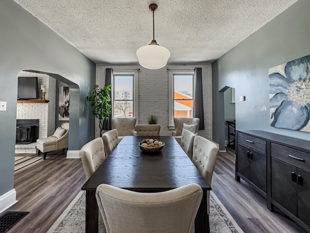 dining space with a textured ceiling, dark hardwood / wood-style flooring, and a wood stove