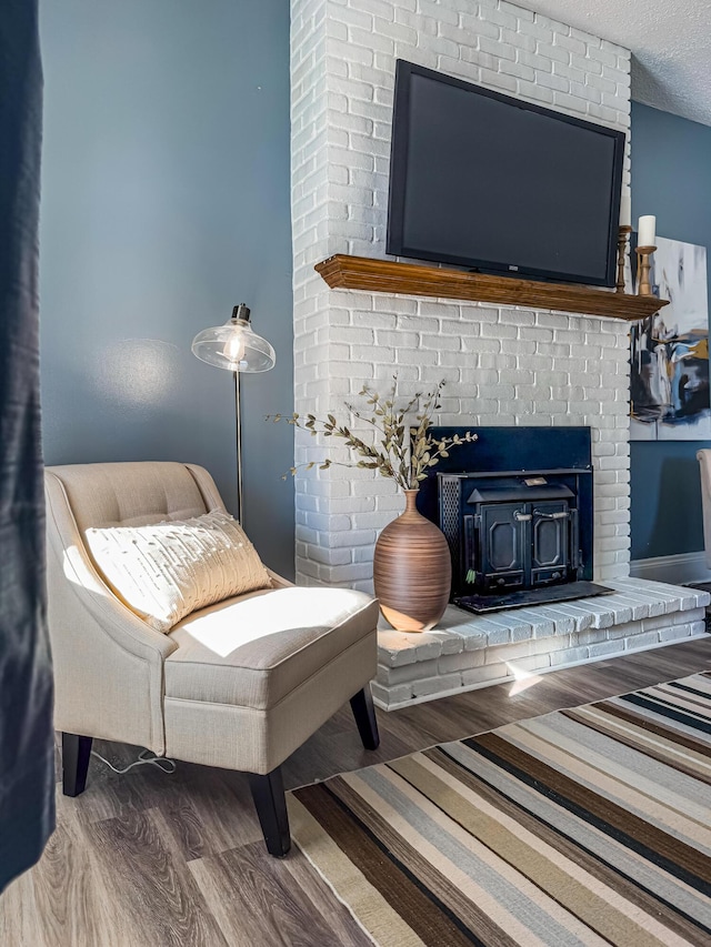 sitting room featuring a textured ceiling, hardwood / wood-style floors, and a wood stove