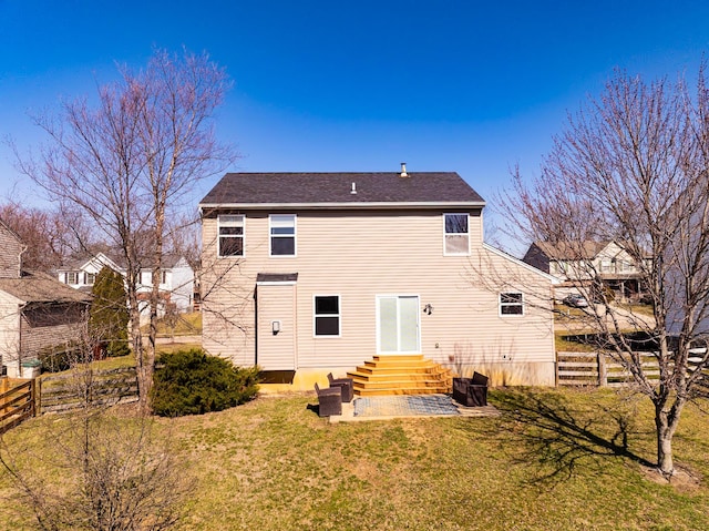 back of house featuring entry steps, fence, a lawn, and a shingled roof