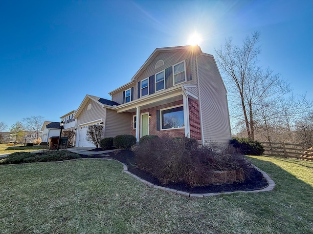 traditional-style home featuring brick siding, a garage, a front lawn, and fence