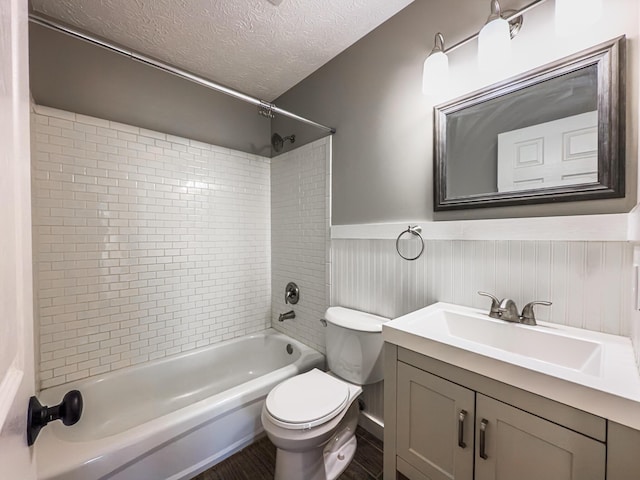 bathroom with vanity, a wainscoted wall, a textured ceiling, shower / tub combination, and toilet