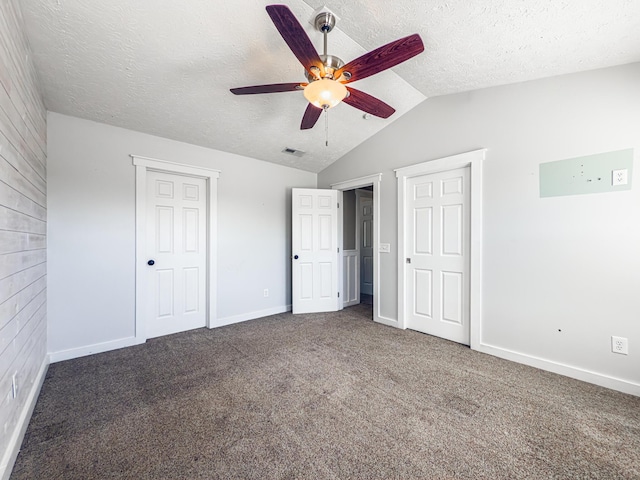 unfurnished bedroom featuring visible vents, a textured ceiling, carpet floors, baseboards, and vaulted ceiling