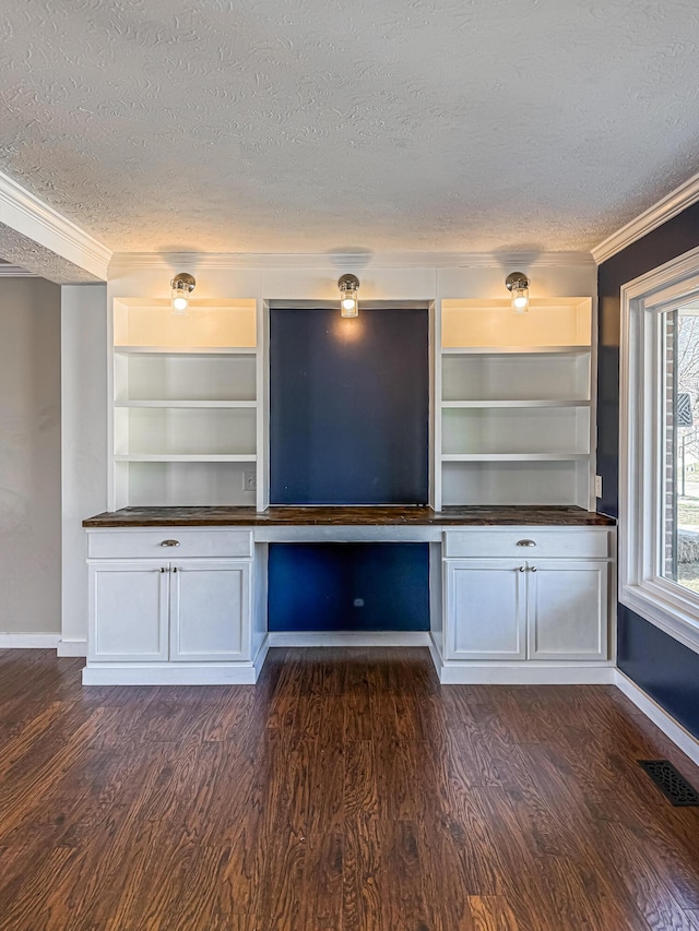 interior space featuring visible vents, a textured ceiling, dark wood-type flooring, and ornamental molding