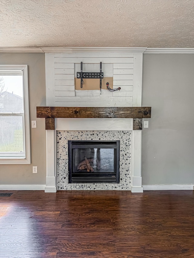 interior details with visible vents, a textured ceiling, wood finished floors, and a tiled fireplace