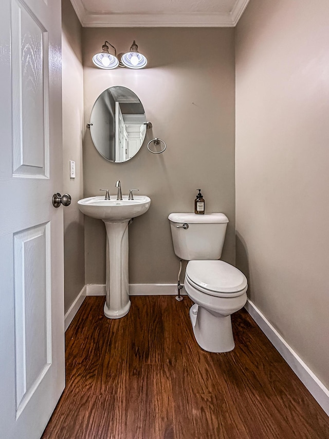 bathroom with baseboards, toilet, wood finished floors, and ornamental molding