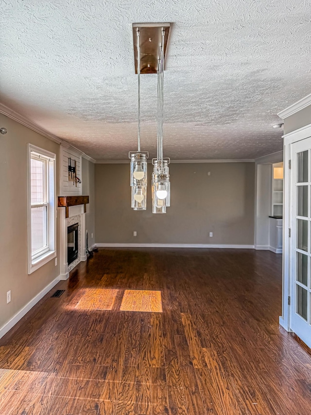 unfurnished living room with a large fireplace, wood finished floors, visible vents, and ornamental molding