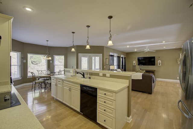 kitchen with light hardwood / wood-style flooring, hanging light fixtures, black appliances, ceiling fan with notable chandelier, and sink