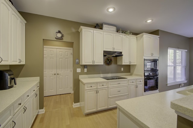 kitchen with white cabinets, black appliances, and light hardwood / wood-style flooring