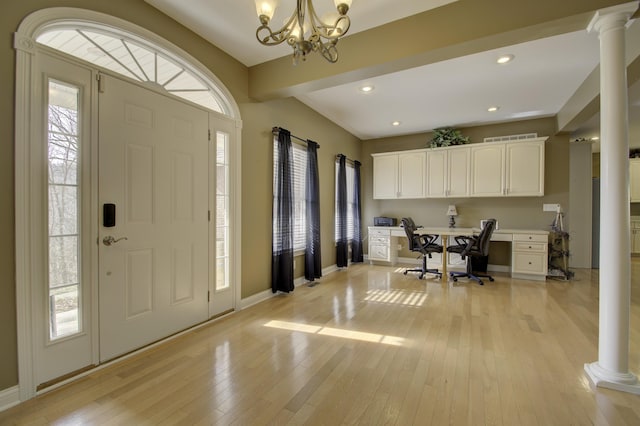 entrance foyer featuring decorative columns, a notable chandelier, and light hardwood / wood-style floors