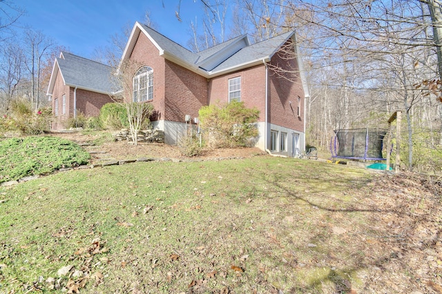 view of side of property with a yard and a trampoline