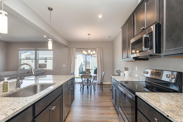 kitchen with decorative light fixtures, sink, an inviting chandelier, appliances with stainless steel finishes, and dark brown cabinetry